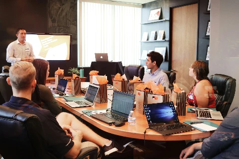 Besprechung an einem großen Tisch mit Laptops